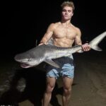 O pescador trata um capa de tubarão muito perigoso como branco branco fechado branco fechado pelo querido ódio.